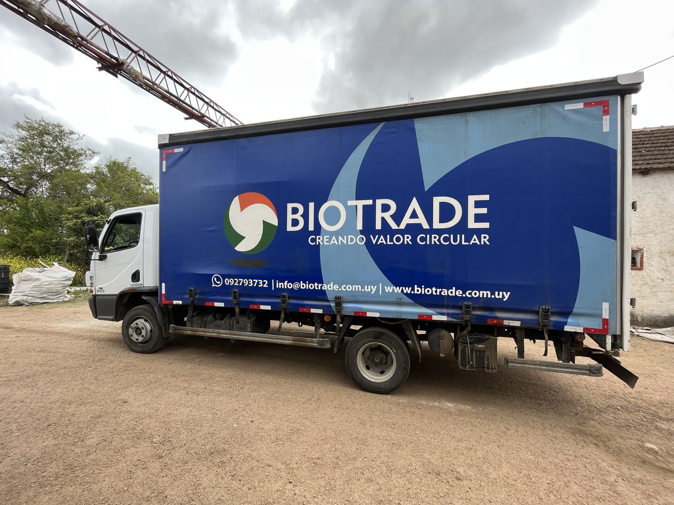 Camión de Biotrade habilitado para el transporte de residuos, con caja cubierta con lona azul, en la planta de Montevideo